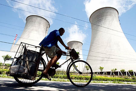 Man Riding Bicycle By Cooling Towers