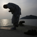 Buddhist monk bows in prayer for missing passengers who were on Sewol ferry, which sank in sea off Jindo, at port in Jindo