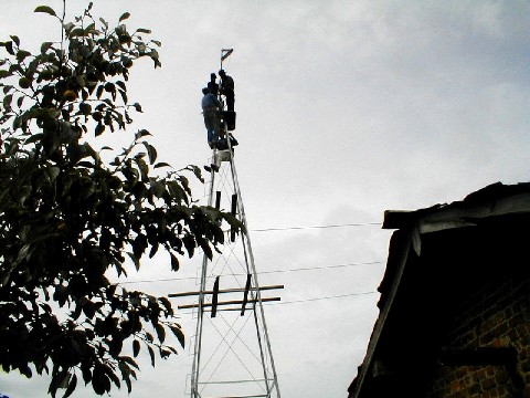 US and DPRK technicians work together atop a high tower.
